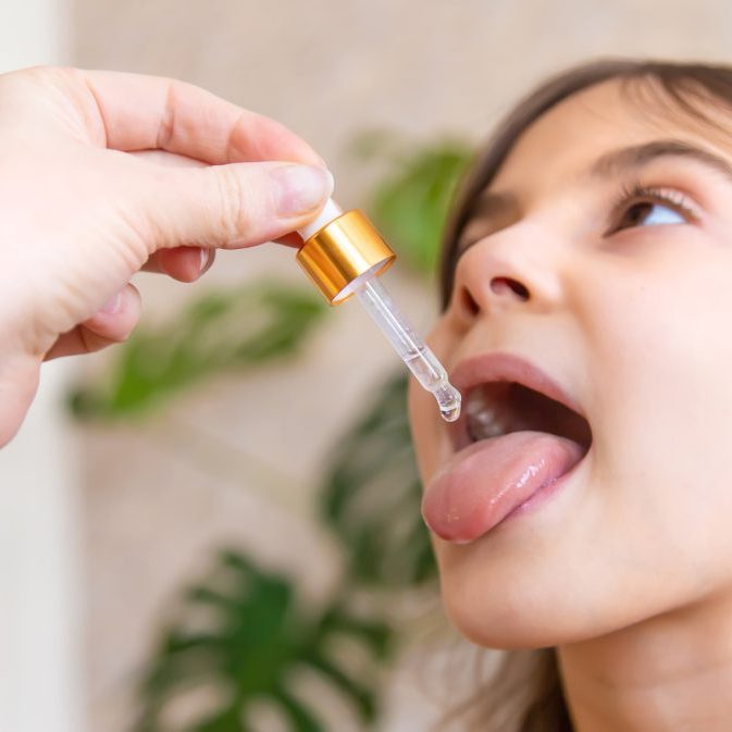 mother giving vitamin drops with dropper to her child. dietary supplements for kids. selective focus.